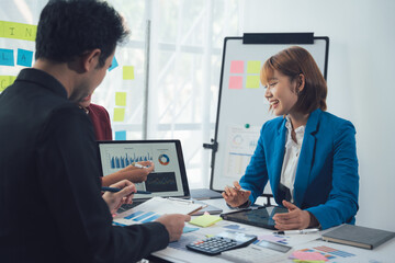 Strategic Business Meeting:  A collaborative discussion unfolds between a diverse team of professionals reviewing data and charts during a productive office meeting.