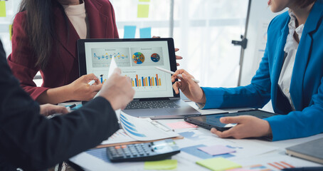 Teamwork Makes the Dream Work: Business professionals collaborate around a laptop displaying key...