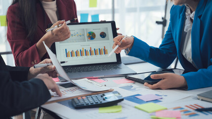 Business Strategy Session: A team of professionals collaborate around a laptop, analyzing charts...