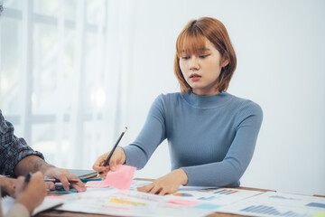 Focused Collaboration: A young businesswoman meticulously reviews project plans, deeply engrossed in her work during a collaborative meeting.