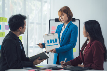 Business Presentation: A focused female executive confidently presents key data and insights to her attentive colleagues during a productive office meeting.