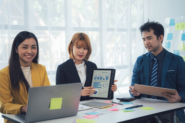 Teamwork Makes the Dream Work: Collaborative business meeting image showing three diverse professionals working together on a project, using laptops and tablets to analyze data and charts.  