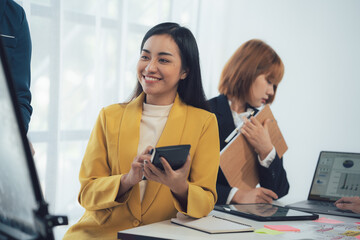 Businesswoman Focused on Strategy: A businesswoman in a yellow blazer smiles confidently as she...