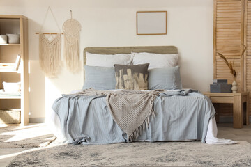 Cozy bed, shelving unit and folding screen in interior of bedroom