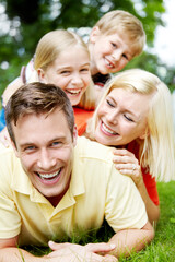 Fototapeta premium Portrait, outdoor and family with kids, funny and bonding together with smile, happiness and laughing. Face, mother and father in backyard, joyful and playing with parents, games and love with care