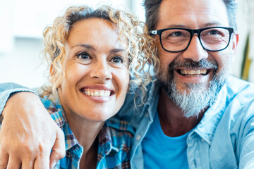 Comfortable on their living room sofa, the couple uses the remote to select a show to watch, smiling warmly at each other as they enjoy a peaceful evening and share positive moments