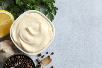Bowl with mayonnaise and ingredients for cooking on gray background