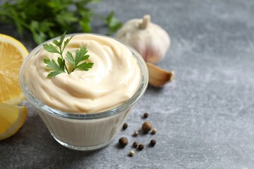 Bowl with mayonnaise and ingredients for cooking on gray background