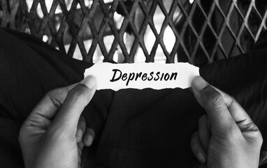 Top view of hand holding torn paper with depression message on black and white background....