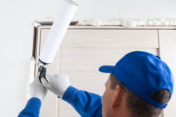 a master in a blue protective uniform installs an interior door, eliminating the gap with mounting...