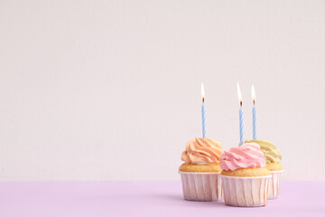 Sweet Birthday cupcakes with burning candles on colorful background