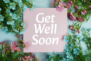 Get well Soon text with flowers frame decoration top view on blue background