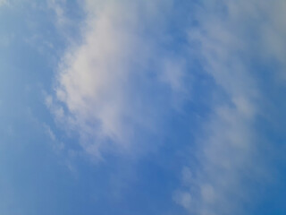 Bright blue sky with soft white clouds, creating a peaceful and serene atmosphere in a clear, open sky view.