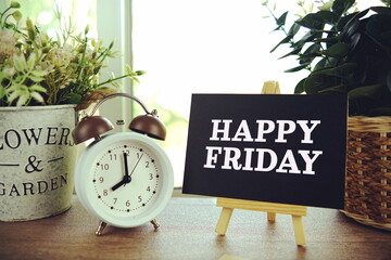 Happy Friday text on paper card with ealsel on wooden background