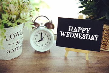Happy Wednesday text on paper card with ealsel on wooden background
