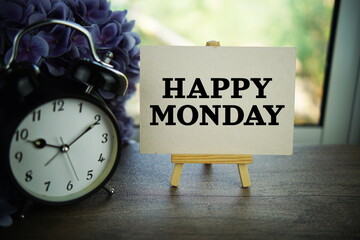 Happy Monday text on paper card with ealsel on wooden background