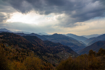 The bright sun is shining brilliantly through the clouds above the mountains
