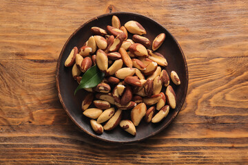 Plate with tasty Brazil nuts on wooden background