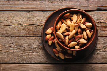 Bowl and plate with tasty Brazil nuts on wooden background