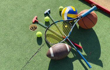 Different sports equipment on green grass, flat lay