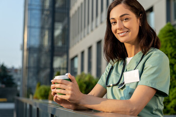 Pretty young female doctor having coffee and looking contented