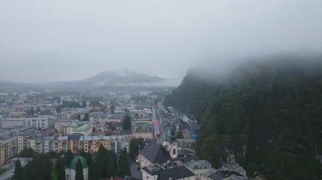 Fog enveloping Salzburg, Austria, creates a mystical ambiance. An aerial perspective reveals the old town and monchsberg hill, highlighting the enchanting landscape
