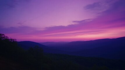 Obraz premium A vibrant purple and pink sunset illuminates the sky over a distant mountain range, creating a picturesque scene.