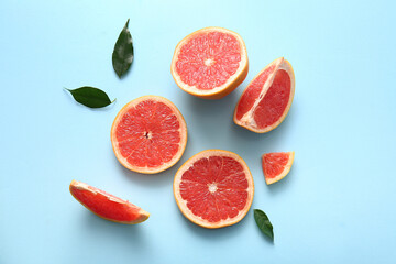 Cut fresh grapefruit and leaves on blue background