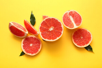 Cut fresh grapefruits and leaves on yellow background