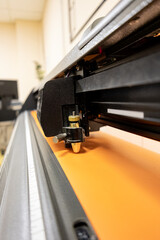 Cutting plotter close-up. The process of cutting a vinyl film. Cutting plotter makes adhesive lettering from vinyl foil