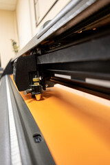 Cutting plotter close-up. The process of cutting a vinyl film. Cutting plotter makes adhesive lettering from vinyl foil