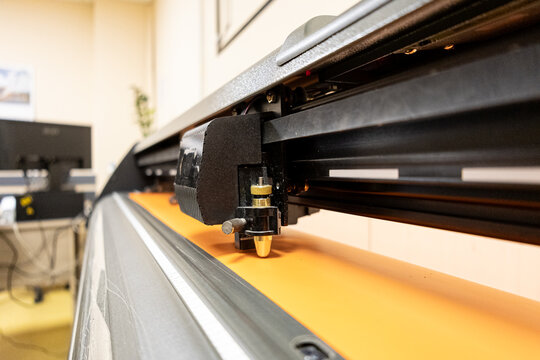 Cutting plotter close-up. The process of cutting a vinyl film. Cutting plotter makes adhesive lettering from vinyl foil