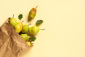 Paper bag with sweet ripe pears on yellow background