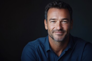 Fototapeta premium a Caucasian man, aged 30s to 50s, in minimal professional clothing, standing confidently with a relaxed, welcoming expression against a gray backdrop.