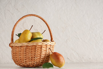 Wicker basket with sweet ripe pears on white background