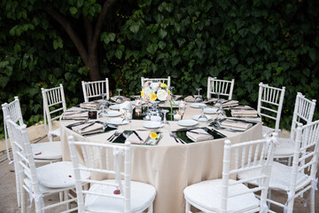 Elegant Outdoor Wedding Table Setting with Floral Centerpiece and White Chairs for a Garden Reception