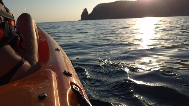 Kayaking Sunset Ocean Coastline - A scenic view of a woman kayaking at sunset with a coastline in the distance.
