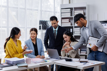 Group of confident business asian people point to graphs and charts to analyze market data, balance sheet, account, net profit to plan new sales strategies to increase production capacity.	