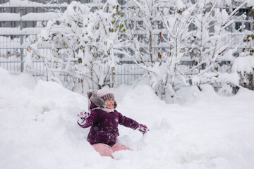 Little girl wearing a cozy winter outfit, happily exploring deep snow. The pure white snow surrounds her, creating a dreamy winter scene full of childhood wonder