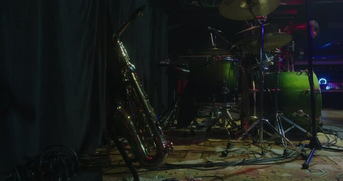 Beautiful slow motion shot of a saxophone and Drum on a concert stage at a sound check as the lights pass over it. There are no people.