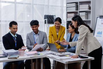 Group of confident business asian people point to graphs and charts to analyze market data, balance sheet, account, net profit to plan new sales strategies to increase production capacity.	