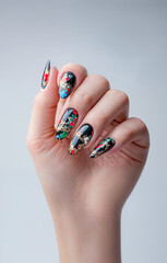 gros plan sur la main d'une femme qui montre ses ongles d&eacute;cor&eacute;s pour les f&ecirc;tes de no&euml;l, tous diff&eacute;rents, avec des motifs color&eacute;s