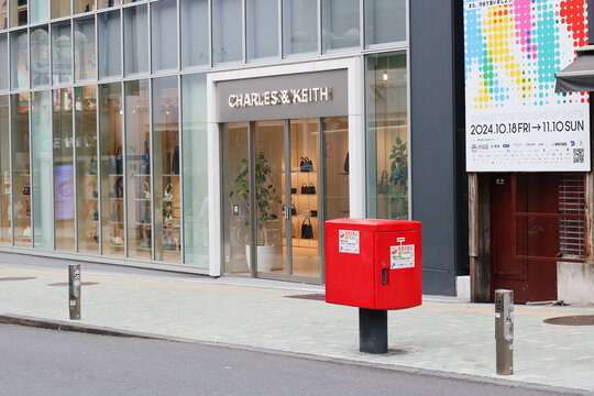TOKYO, JAPAN - November 6, 2024: Street in Tokyo's Shibuya area with a Charles and Keith store, a postbox and a billboard advertising Social Innovation Week Shibuya.