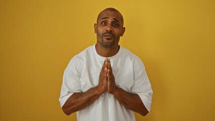 Handsome man making a gesture with hands together against an isolated yellow background, conveying...