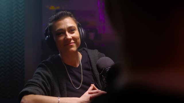 Androgyne girl is a guest on the podcast. A lesbian woman is talking to a journalist, listening to the speaker's speech. They discuss psychology and LGBT issues on a radio show. Female butch
