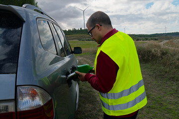 Technician refueling company car near wind turbine power plant