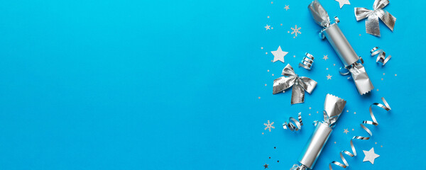 Christmas crackers with shiny confetti on color background, top view, copy space