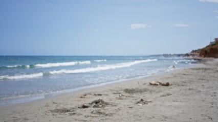 Blurred beach scene with waves, sand, and sky in an outdoor setting