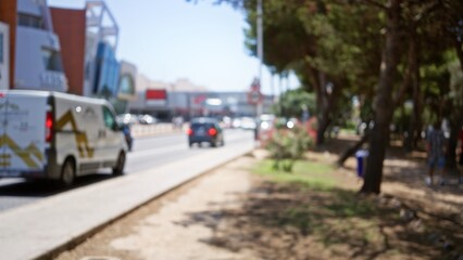 Blurred outdoor urban scene with defocused cars, people, trees, and buildings under a bright sunny sky