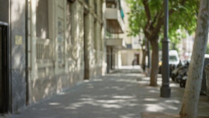 Fototapeta premium Blurred sidewalk in an urban outdoor setting with defocused buildings and trees creating a bokeh effect in the background on a sunny day